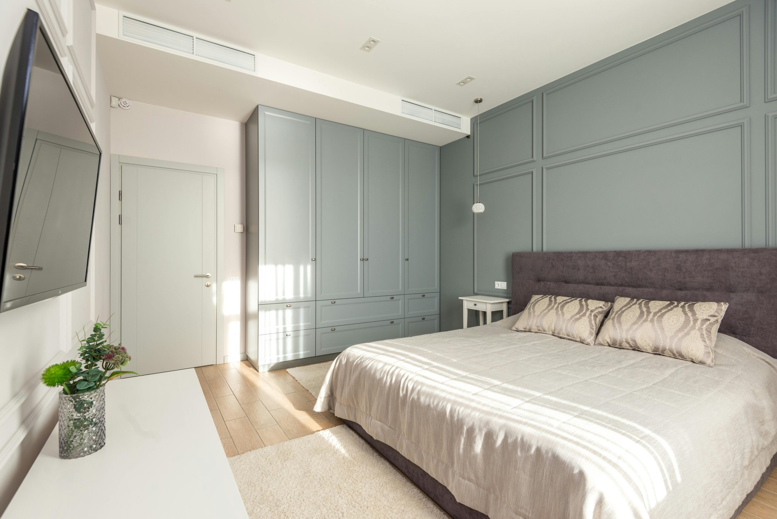 Guļamistaba ar zaļu sienas skapi un dekoratīvo sienas apdari 